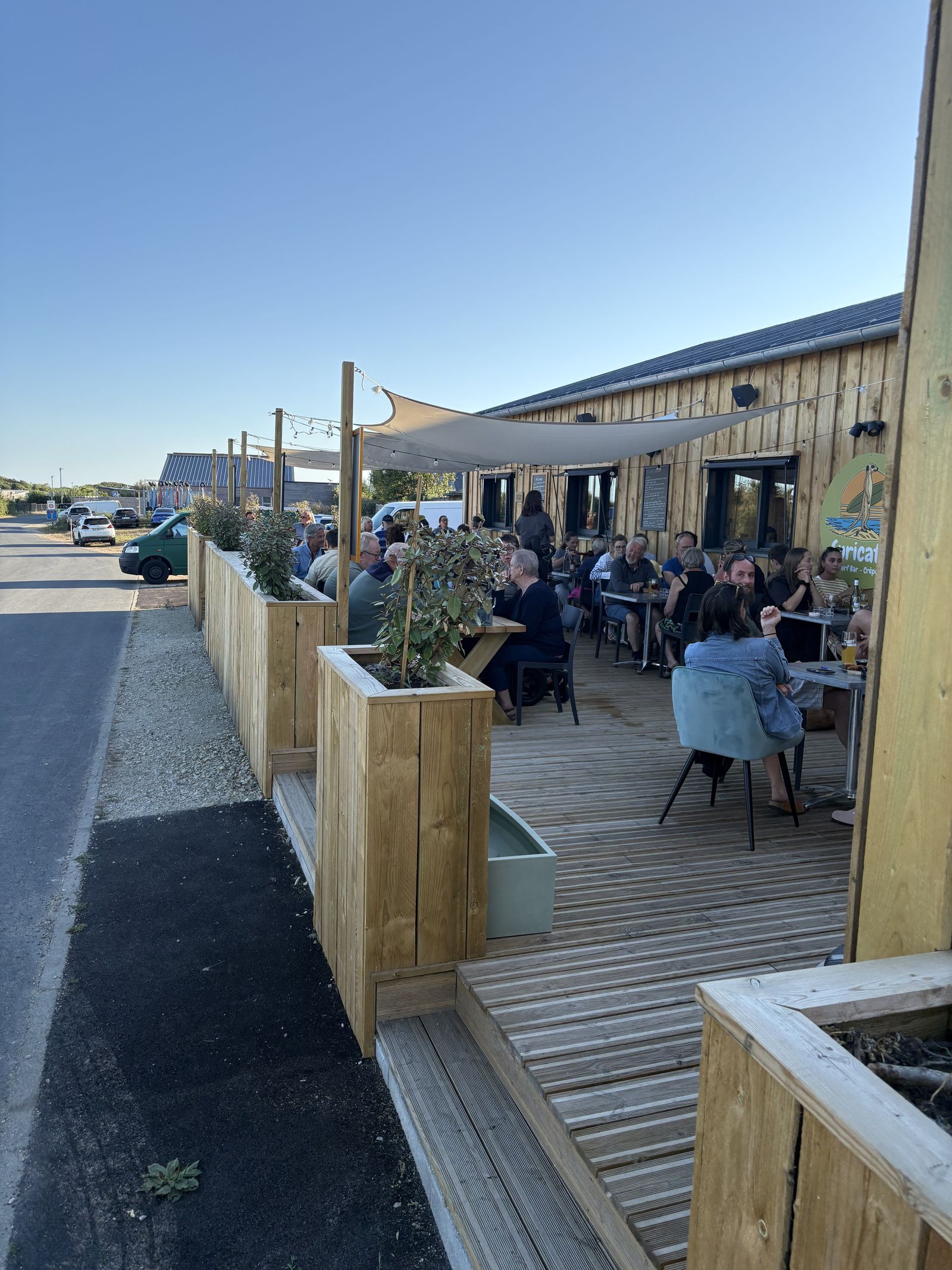 The wooden terrace along the road, full of guests in the sunshine.
